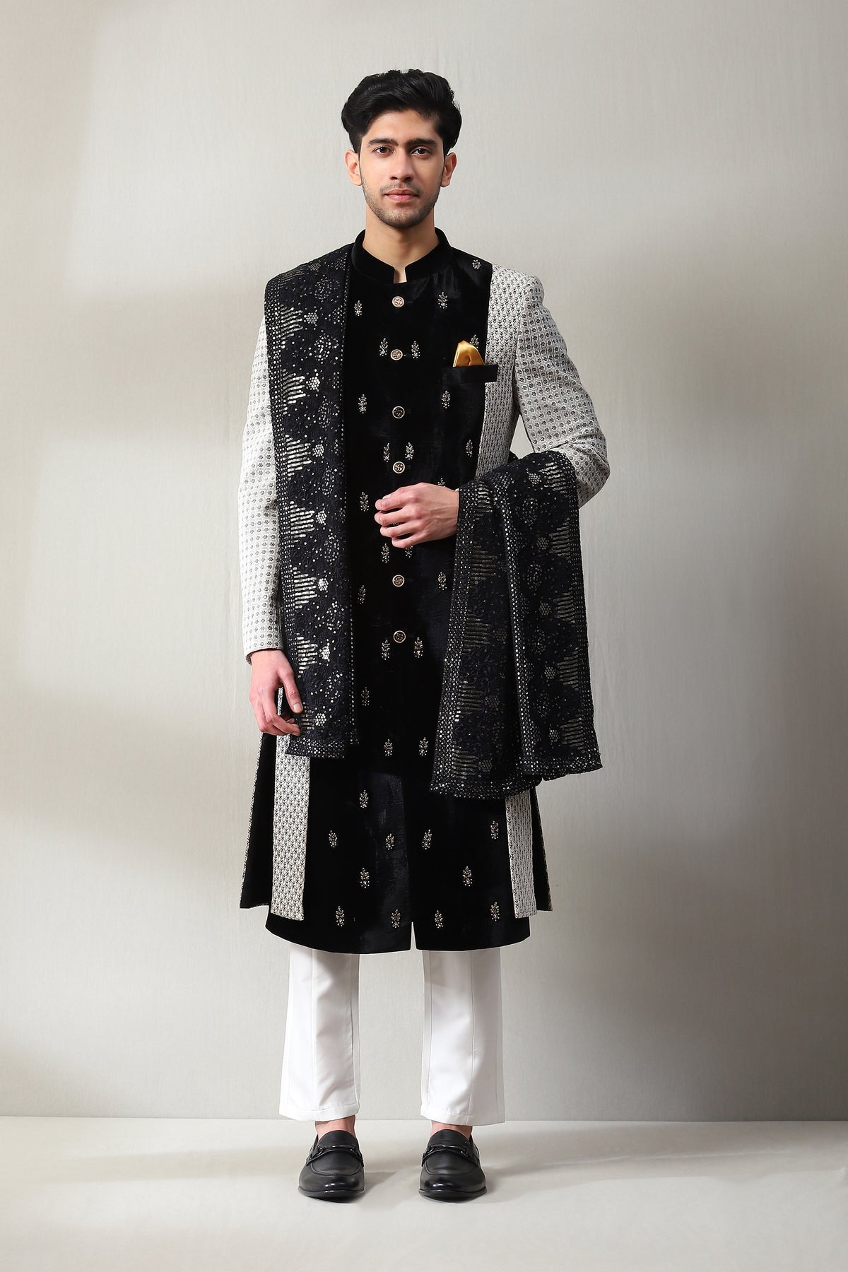 This ivory sherwani is embedded with thread work, has an Embroided black velvet panel with hand embroidery on it