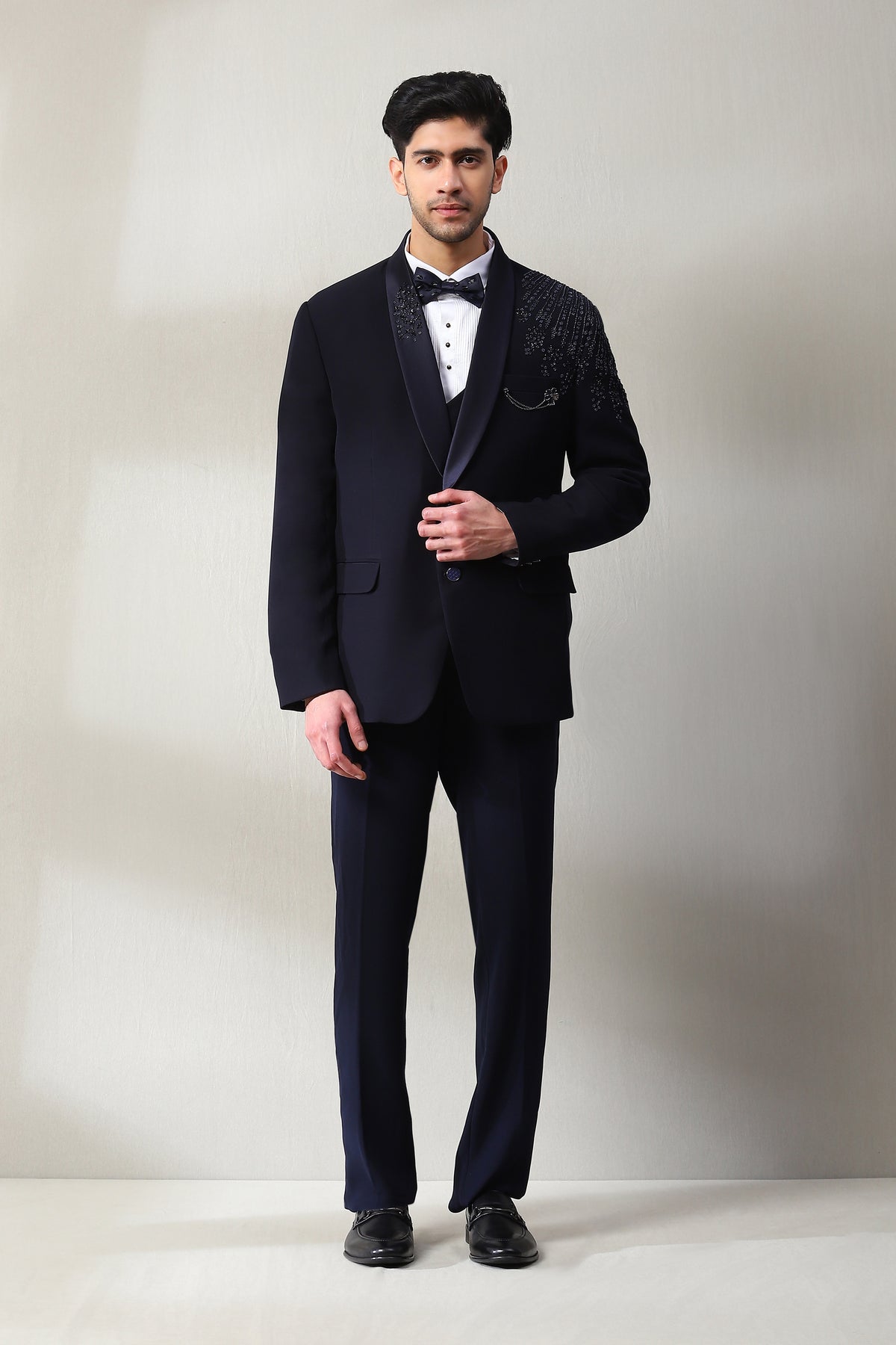 This classy Italian fabric black tuxedo is adorned with hand work